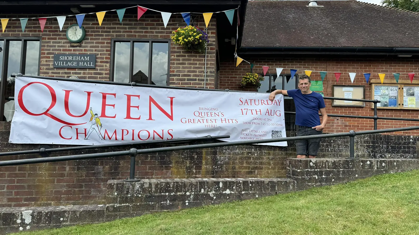 Matt from Queen Champions beside the band banner outside Shoreham Village Hall before their first show