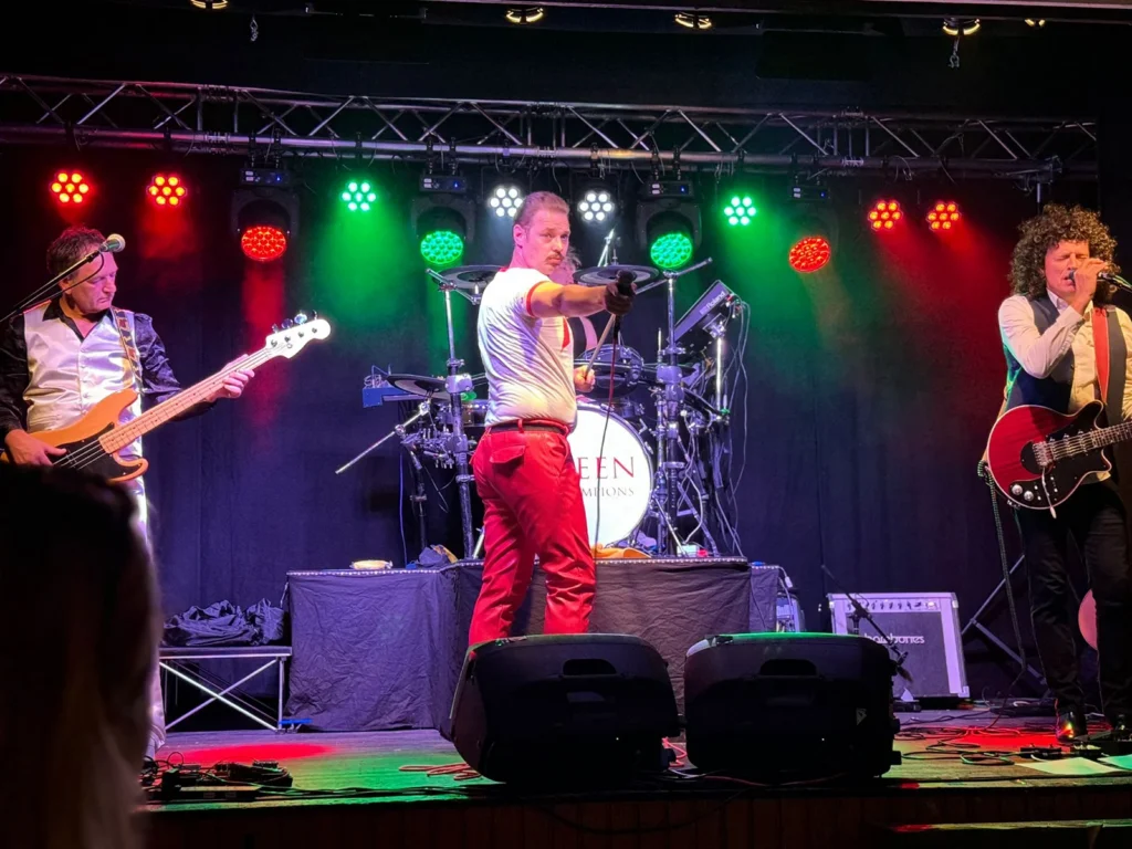 Queen Champions performing live on stage with the audience in the foreground